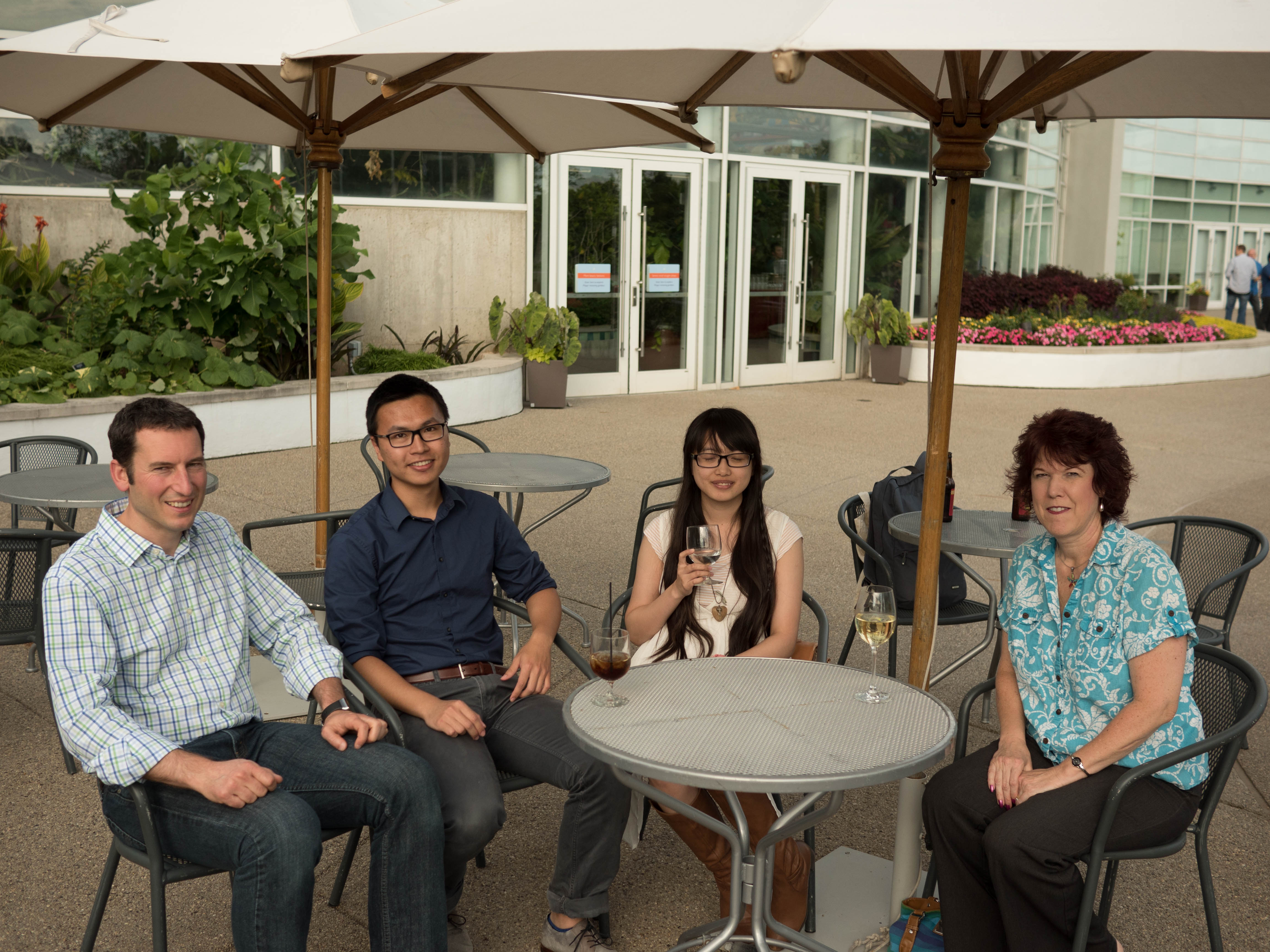Four attendees seated at an outdoor patio table under umbrellas during the MLSS 2014 welcome reception